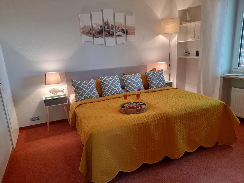 - une chambre avec un grand lit et un couvre-lit jaune dans l'établissement Apartments Domicil Alice, à List auf Sylt