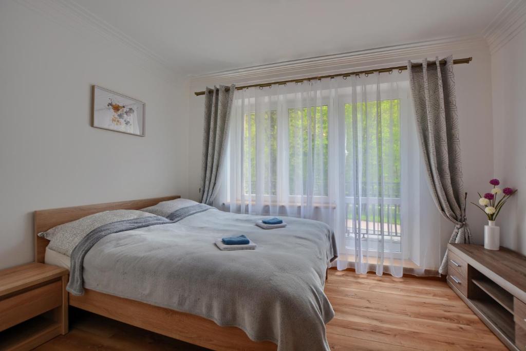 a bedroom with a bed and a large window at Willa Białe Tarasy in Krynica Zdrój