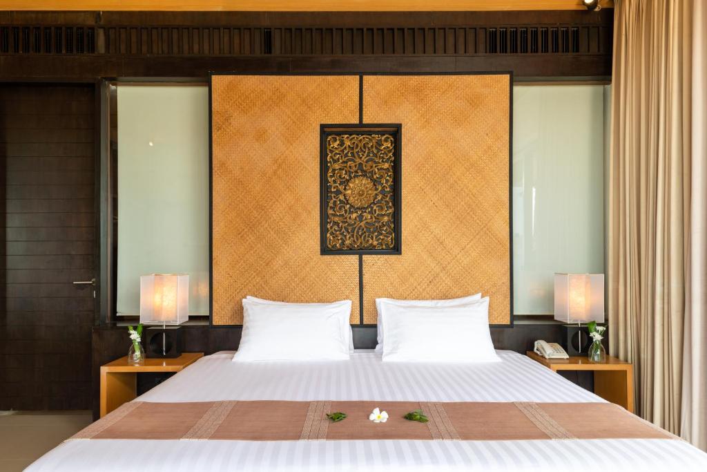 a bedroom with a large bed with two pillows at Baan Krating Phuket Resort -SHA Plus in Nai Harn Beach