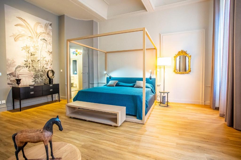 um quarto com uma cama azul e uma estátua de cavalo em Le Belem em Carcassonne