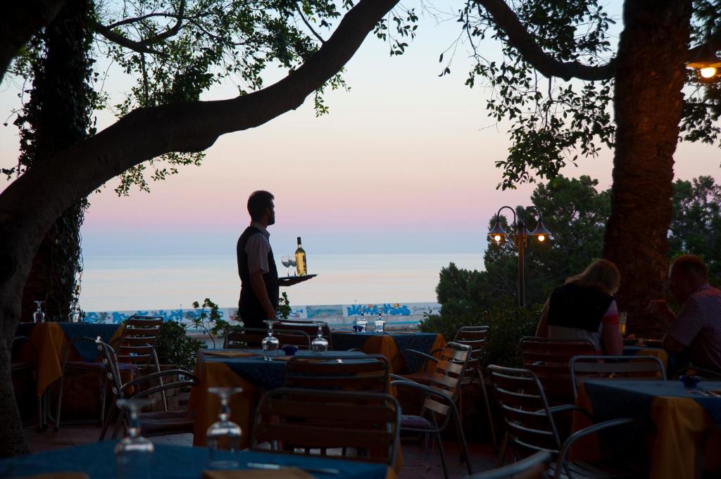 a man standing at a table with a bottle of wine at Albergo Miramare in Cala Gonone