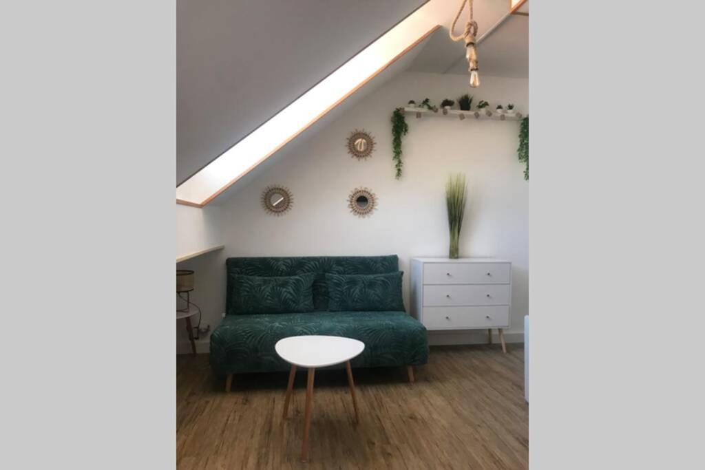 un salon avec un canapé vert et une table dans l'établissement charmant studio bord de mer, à Menton
