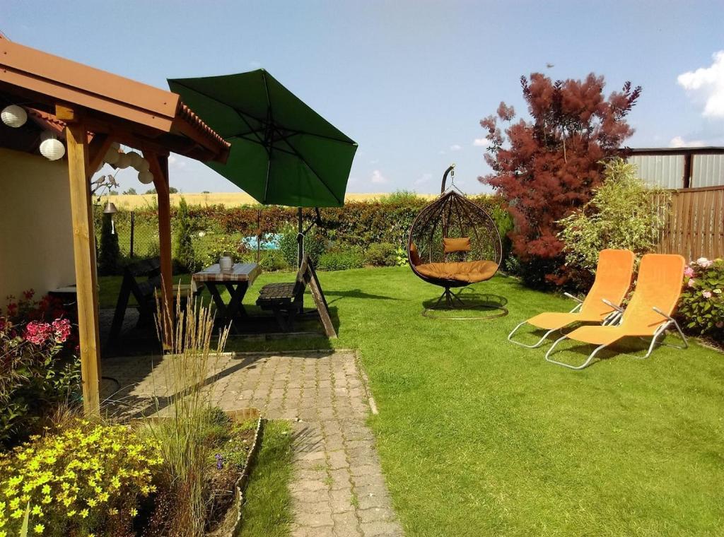 un jardín con 2 sillas y una sombrilla verde en Tumidaj Cottage, en Bogacko
