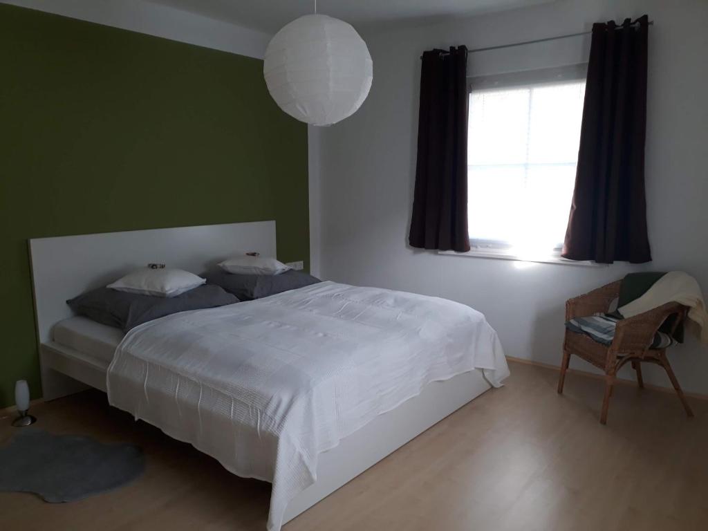1 dormitorio con cama blanca y ventana en Apartement am Waldrand, en Bad Wildbad