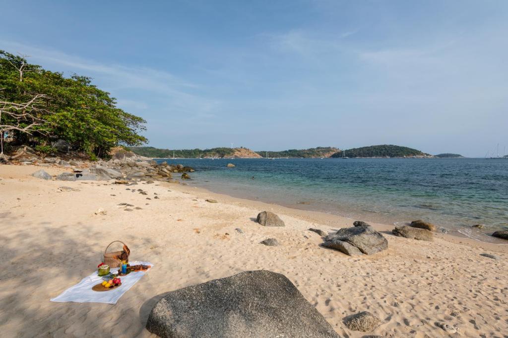 a beach with rocks and a basket on the sand at Baan Krating Phuket Resort -SHA Plus in Nai Harn Beach