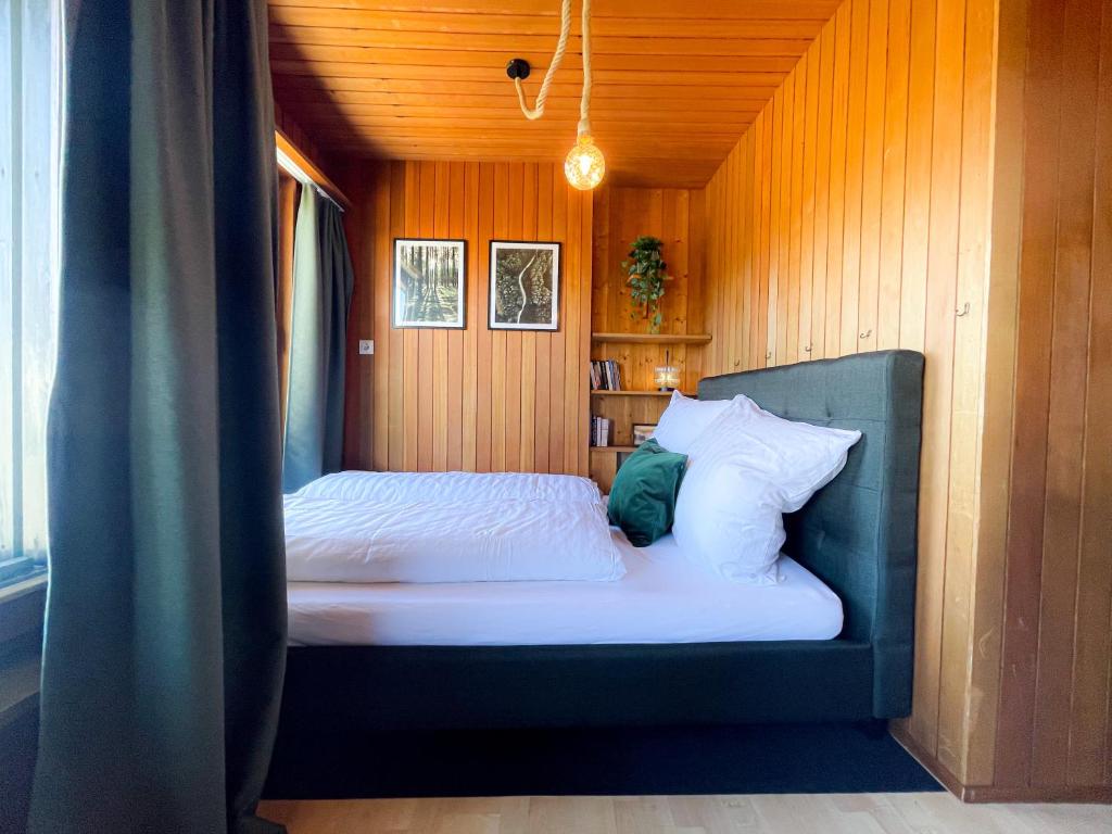 a bed in a room with a wooden wall at Gemütliche Ferienwohnungen mit Pool & Sauna in Höchenschwand
