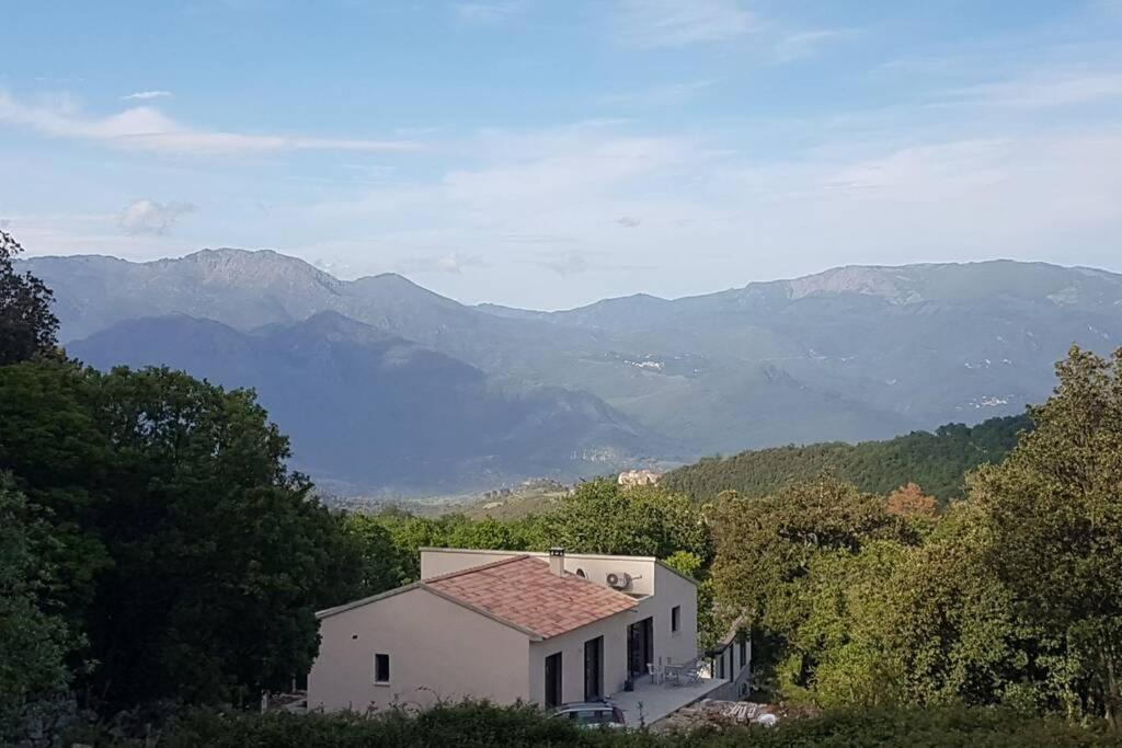 uma pequena casa branca com montanhas ao fundo em VILLA Adrien , maison de charme. em Casanova