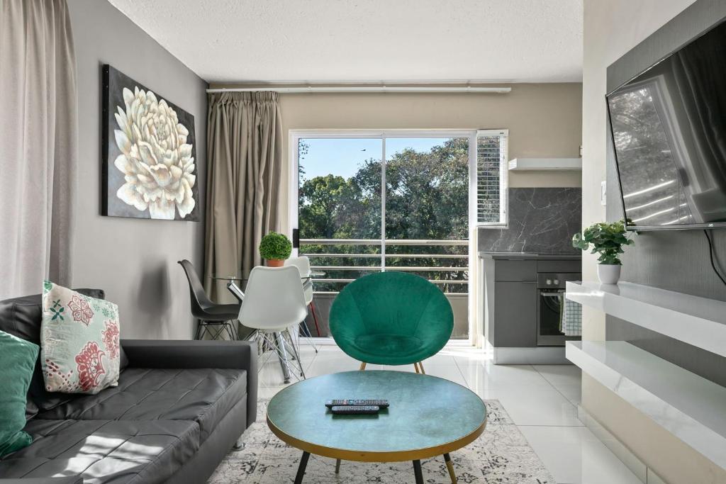 sala de estar con sofá y silla verde en Marley on Katherine Apartments, en Johannesburgo