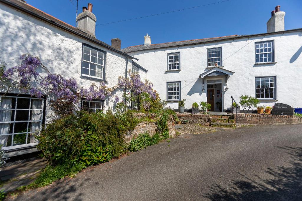 Uma casa branca com flores roxas à frente. em Stratton Gardens em Bude