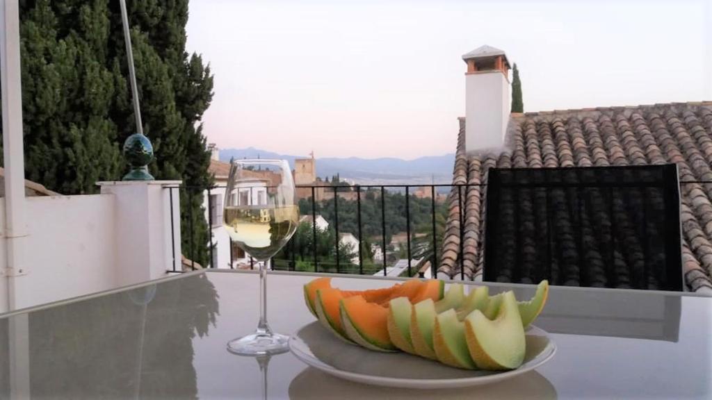 un plato de fruta y una copa de vino en una mesa en Carmen de las Campanas, en Granada