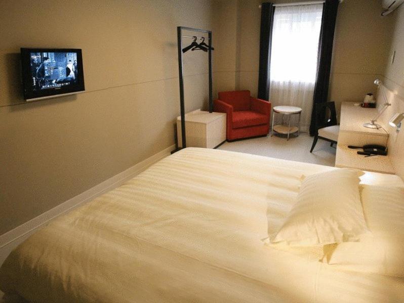 - une chambre avec un grand lit blanc et une chaise rouge dans l'établissement Jinjiang Inn Changsha Dongfeng Road, à Changsha