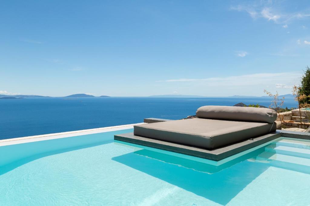 a pool with a bed and the ocean in the background at Olon Villa in Schinias