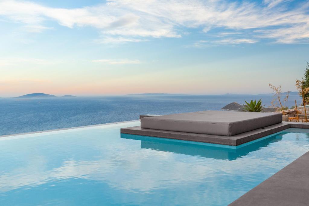 a swimming pool with a bed and the ocean at Olon Villa in Schinias