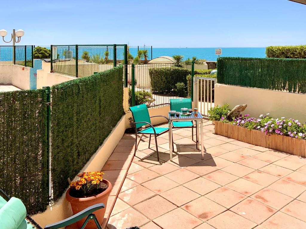 un patio avec deux chaises et une table et une clôture dans l'établissement Le Zéphyr, superbe appartement à la Corniche avec parking, à Sète