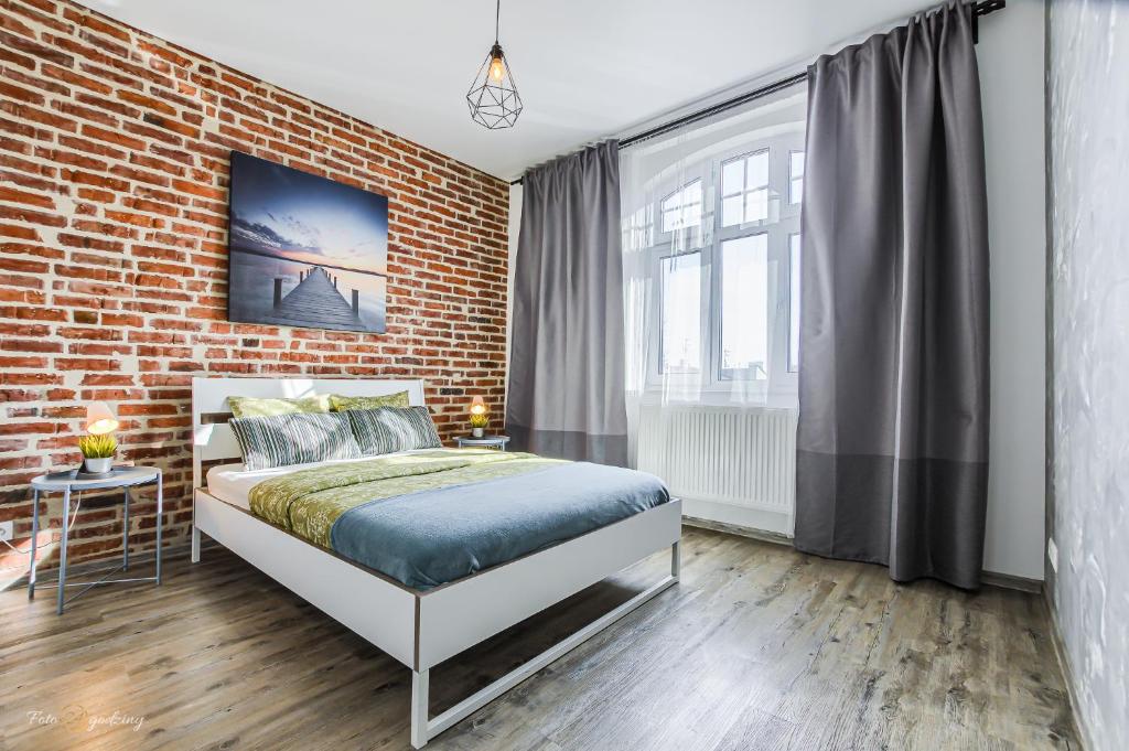 a bedroom with a brick wall and a bed at Apartament SweetDream in Katowice