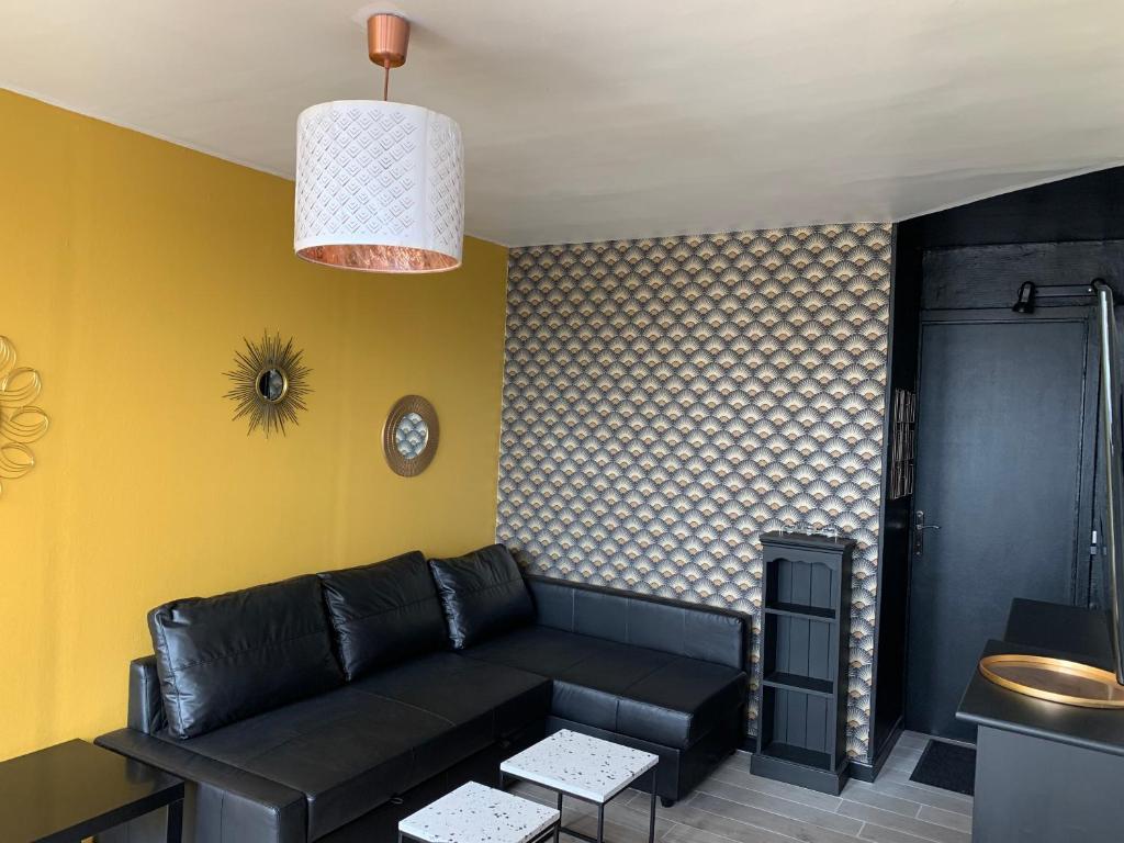 a living room with a black couch and yellow walls at Les Pieds dans l'eau - Locations ISAHORA in Le Tréport