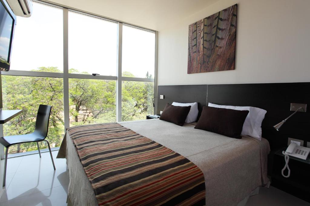 a bedroom with a large bed and large windows at Niyat Urban Hotel in Resistencia