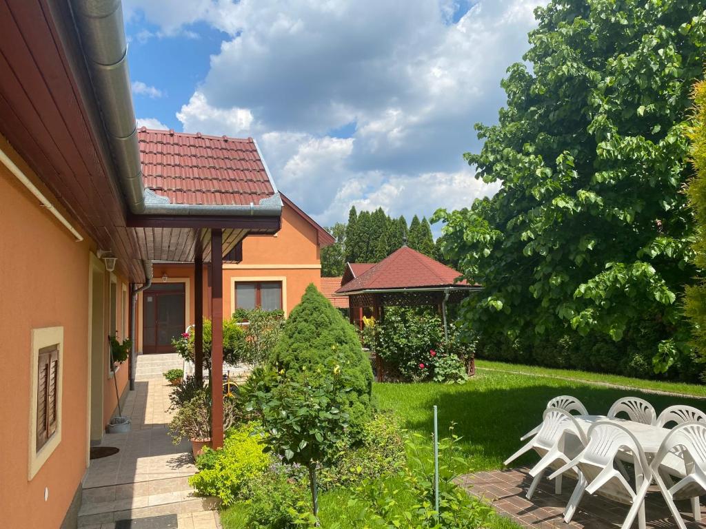 einen Garten mit weißen Stühlen und ein Haus in der Unterkunft Apartman Dóra in Hajdúszoboszló