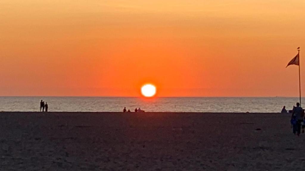 een zonsondergang op een strand met mensen op het strand bij Paradis Studios in Archangelos