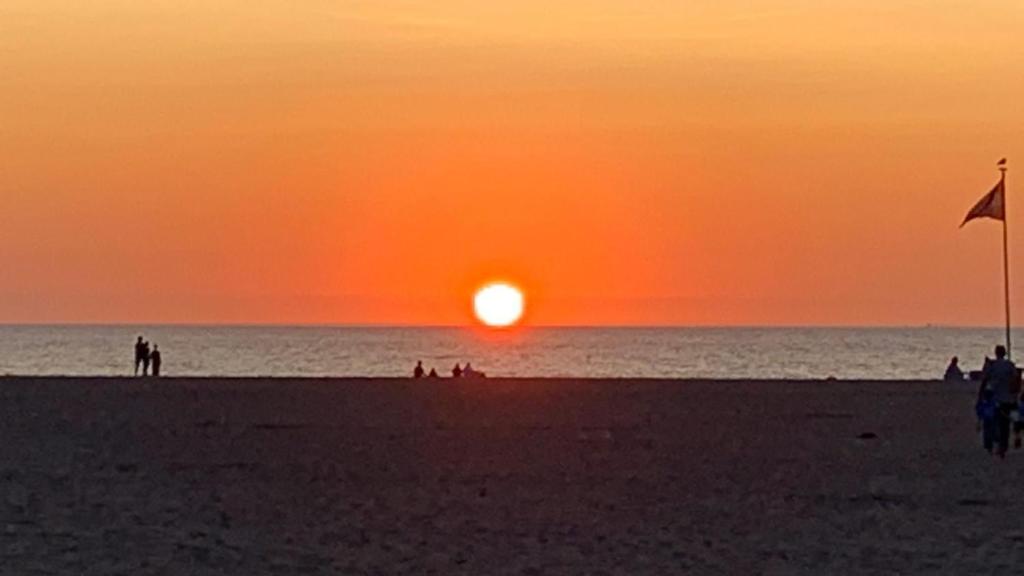 una puesta de sol en una playa con gente en la playa en Paradis Studios, en Archangelos