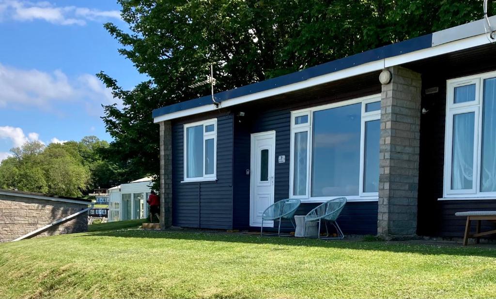 a blue tiny house with two chairs in the yard at Woodlands Pheasant Chalet, Bideford Bay in Bideford