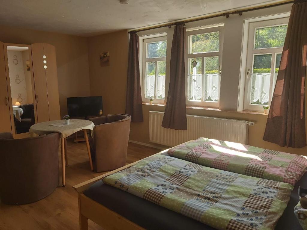 Schlafzimmer mit einem Bett, einem Tisch und Fenstern in der Unterkunft Ferienapartmenthaus am Rittertor in Stolberg i. Harz