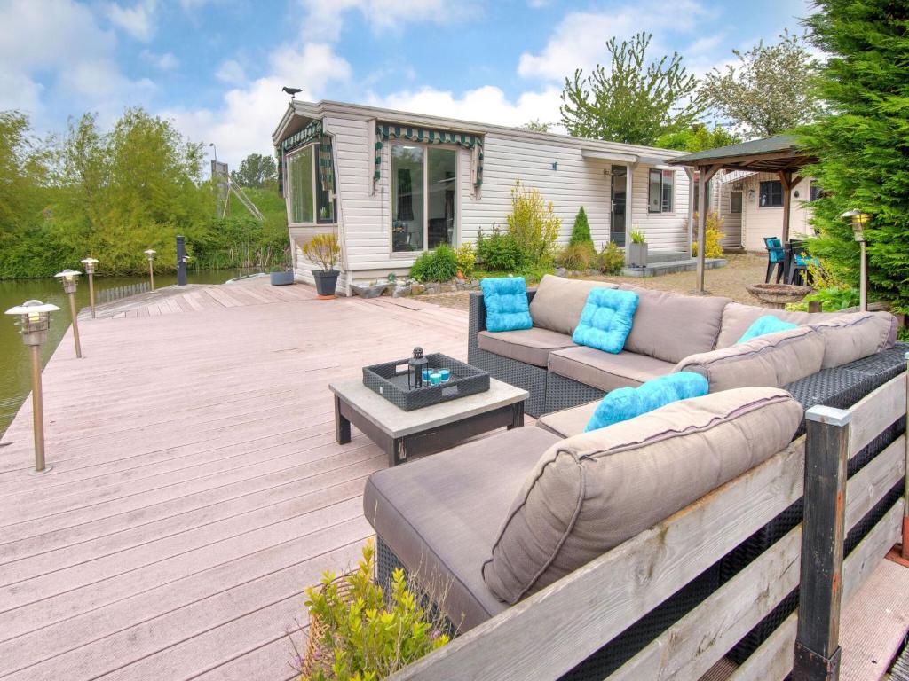 een patio met een bank en een tafel op een terras bij Fantastic villa in Ooltgensplaat with jetty in Ooltgensplaat