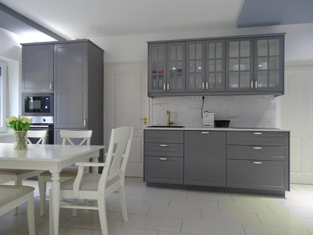 una cocina con armarios grises y una mesa y sillas blancas. en Dorothy Apartman, en Siófok