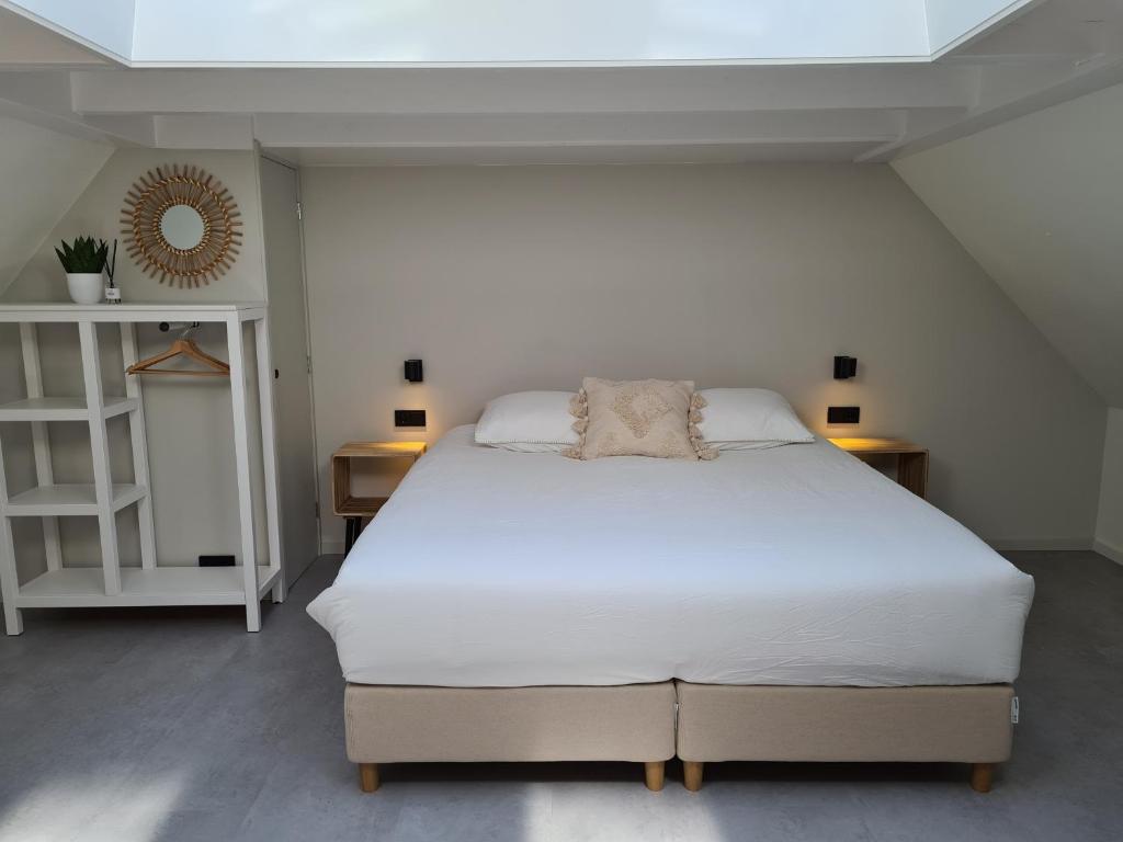 1 dormitorio con 1 cama blanca y 2 mesitas de noche en B&B Onderderietenkap, en Heerde