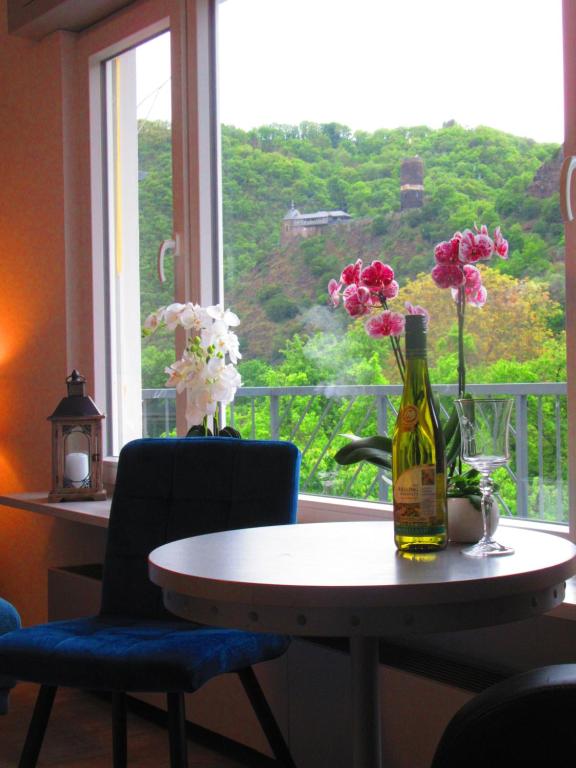 a table with a bottle of wine and flowers on a window at Fewo Himmelblau in Burgen