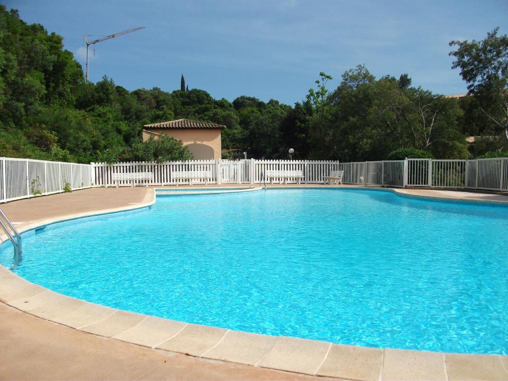 une grande piscine bleue avec une clôture blanche dans l'établissement Bel appartement climatisé - Résidence avec piscine, à Cavalaire-sur-Mer