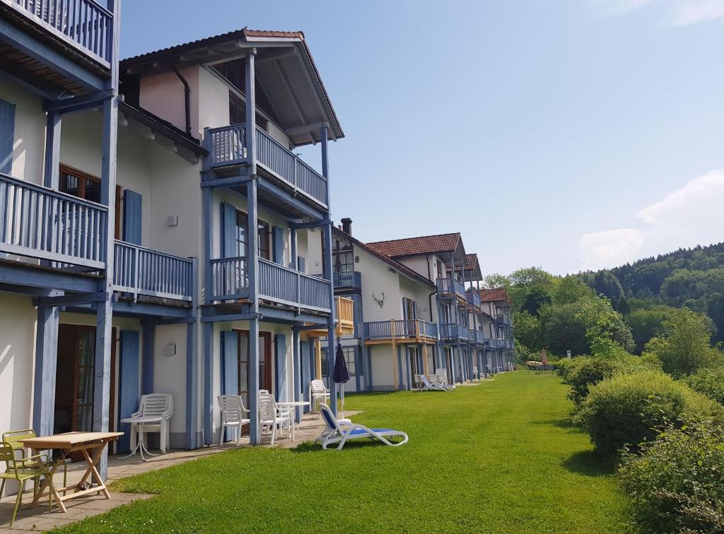 une rangée de bâtiments avec des chaises et des tables dans une cour dans l'établissement Ferienwohnung 32 im Ferienland Sonnenwald - Bayerischer Wald, à Schöfweg