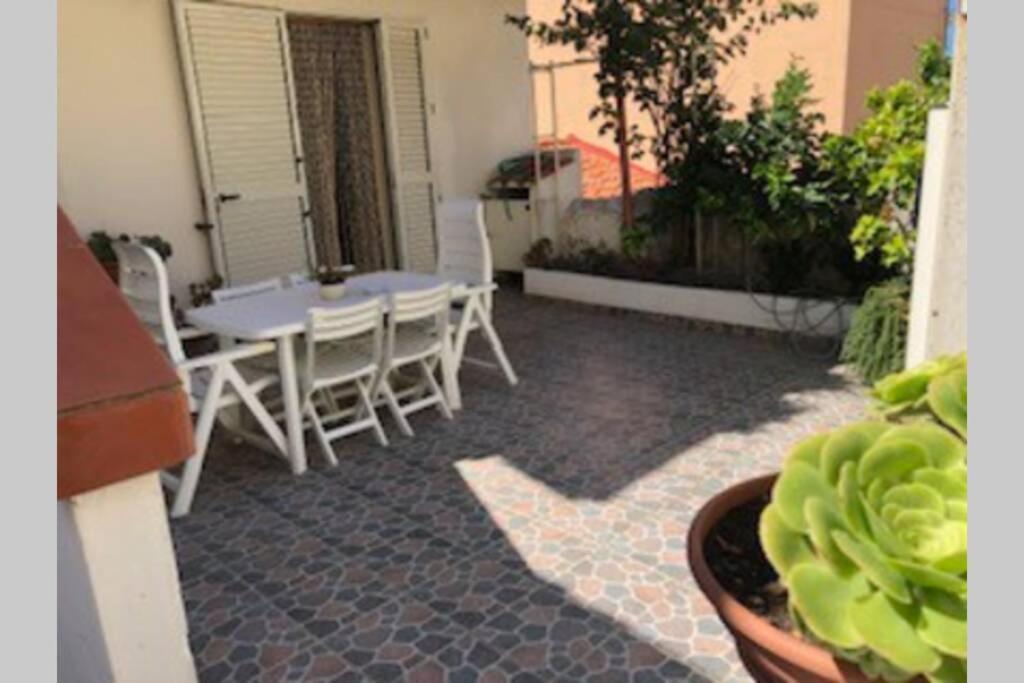 布傑魯的住宿－Buggerru la bomboniera，庭院配有白色的椅子、桌子和桌子以及桌椅。