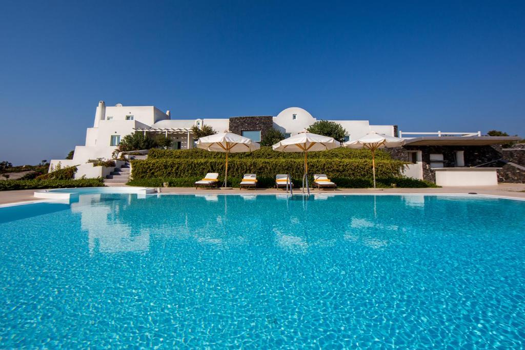 a large pool with chairs and umbrellas in front of a building at Black Rock in Akrotiri