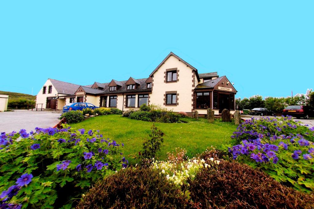 a house with flowers in front of it at Doune Braes Hotel in Breasclete