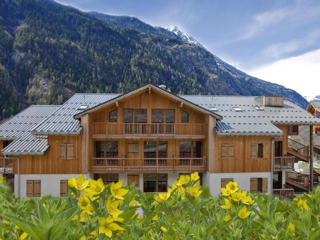a large wooden house with a mountain in the background at ORELLE VALLEE DE LA MAURIENNE in Orelle