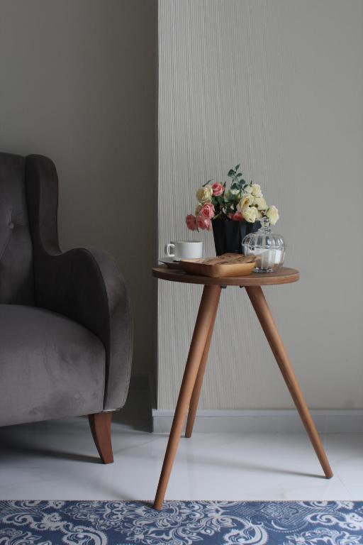 a table with a vase of flowers on it next to a chair at Horizons Hotel Rooms in Batumi