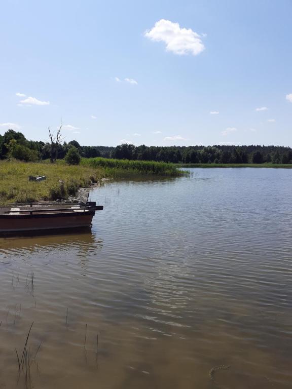 a boat sitting in the water on a lake at Domek w sadzie na Mazurach in Stręgielek