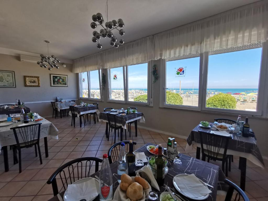 een eetkamer met tafels en stoelen en de oceaan bij Hotel VistaMare Viserba in Rimini