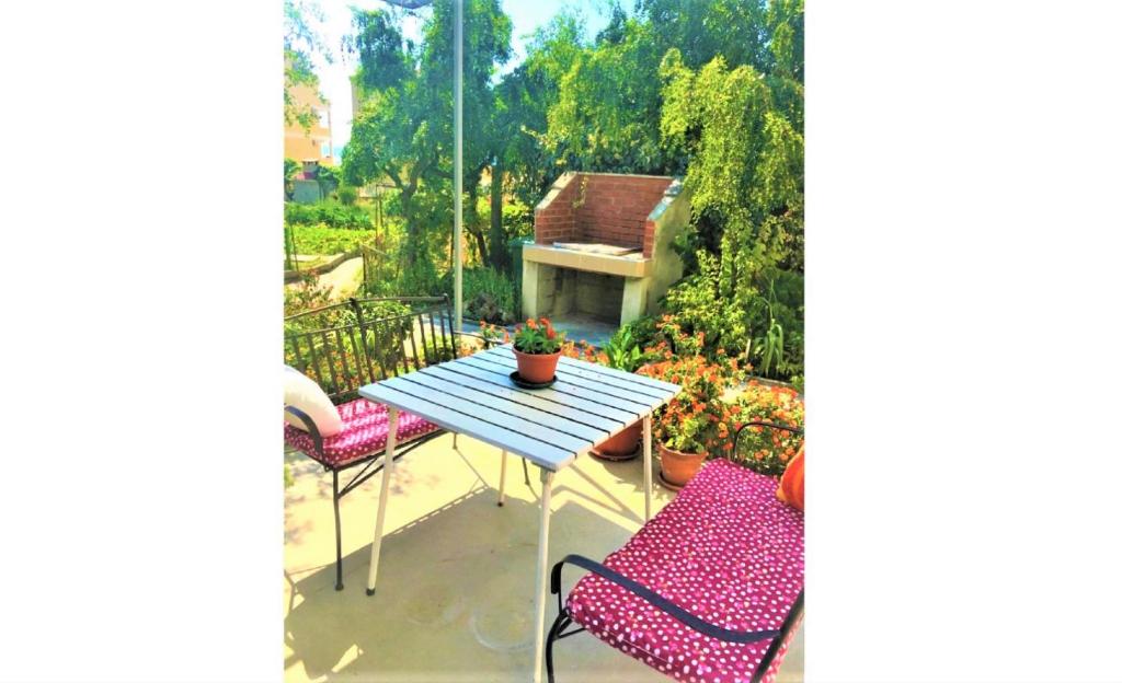 patio con mesa y sillas en el balcón en Apartments Garden House, en Podgora