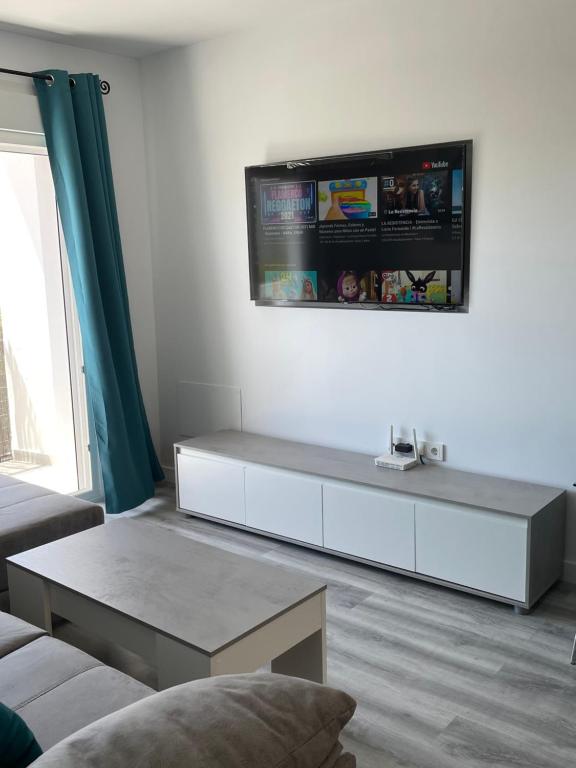 uma sala de estar com um sofá e uma televisão na parede em Apartamento BellaThalía em Ayamonte