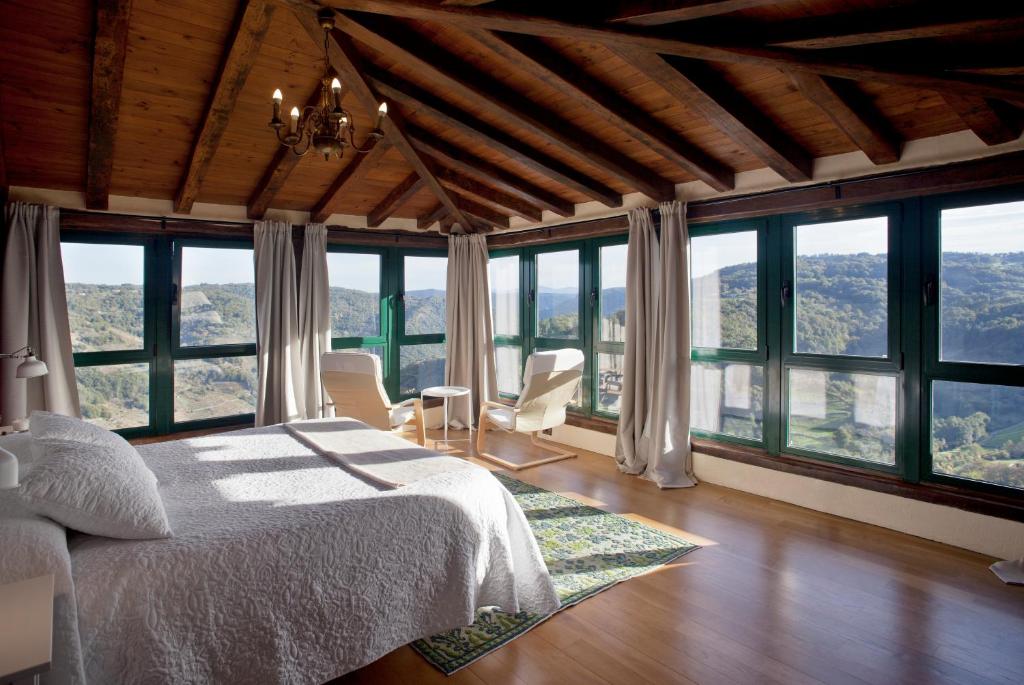 a bedroom with a bed and large windows at Casa Vistaboa Ribeira Sacra in Chantada