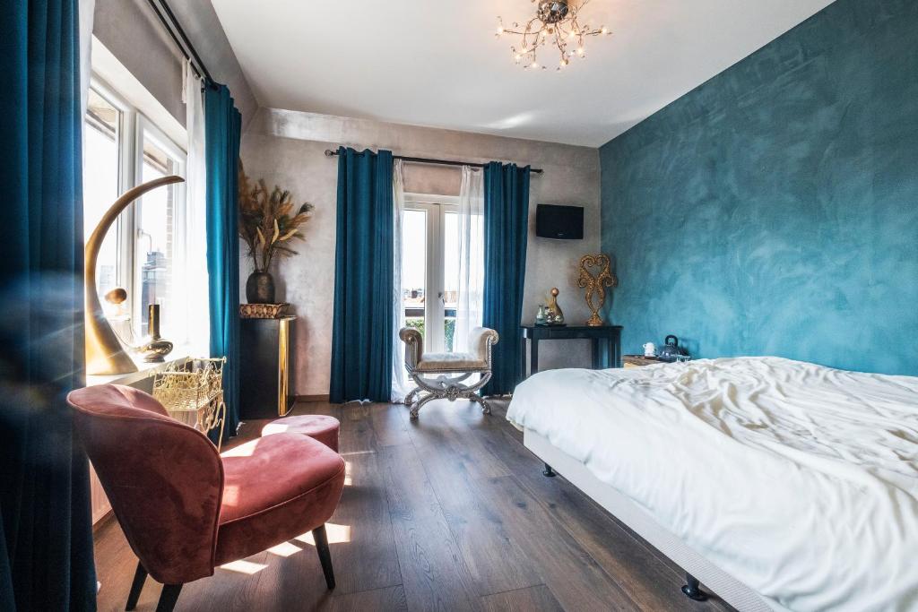 - une chambre avec des murs bleus, un lit et une chaise dans l'établissement Mylos Studios, à Alkmaar