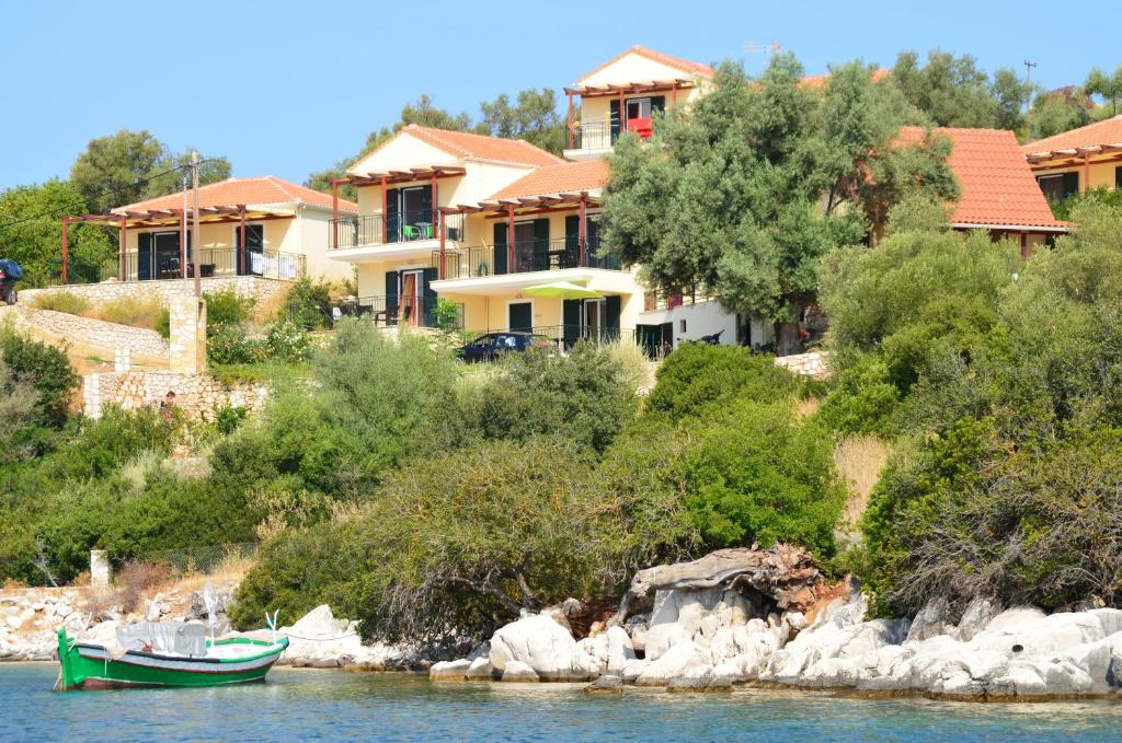 un barco verde en el agua frente a las casas en Elia Village, en Meganisi