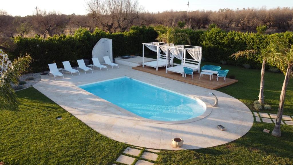 Una piscina en un patio con sillas alrededor. en Trullo TerraNostra villa con piscina Torre San Giovanni, en Ugento