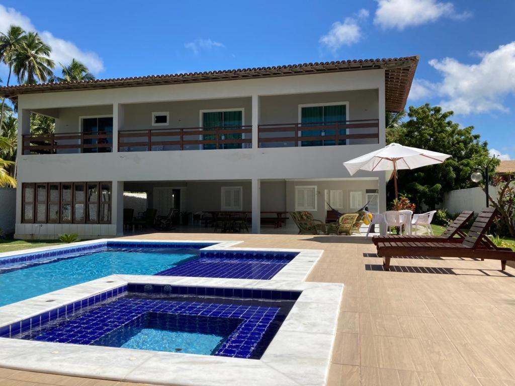 a villa with a swimming pool and a house at Ampla Casa na beira mar de Maragogi in Maragogi