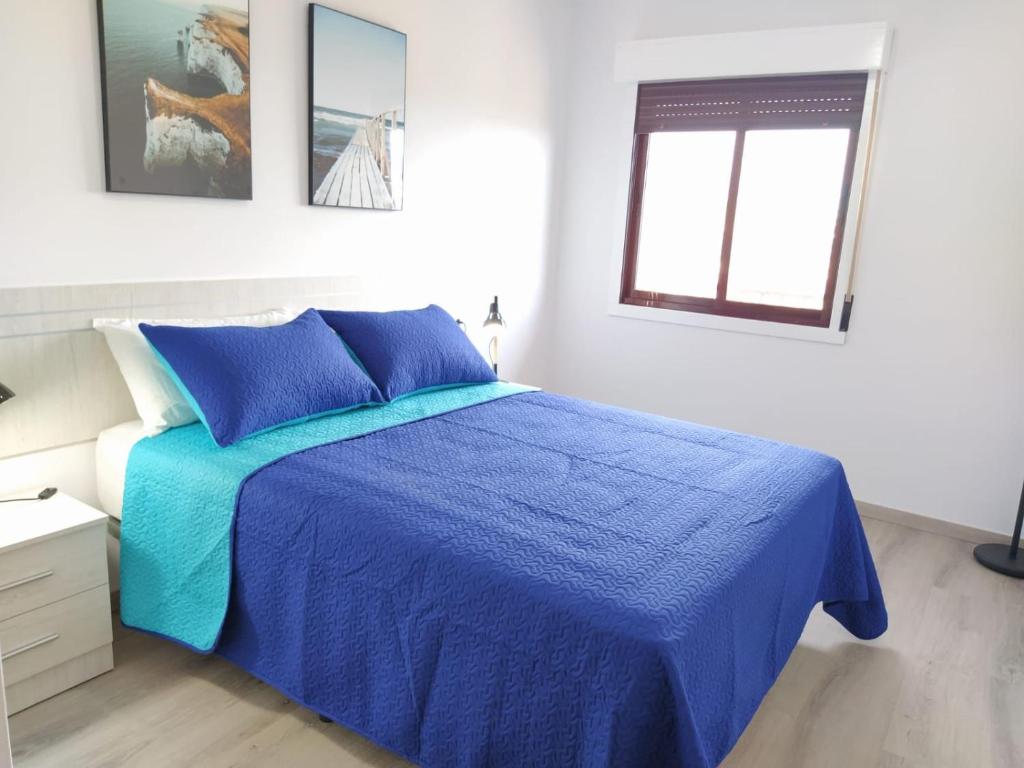 Un dormitorio con una cama azul y una ventana en Ca L´Ana en Tazacorte