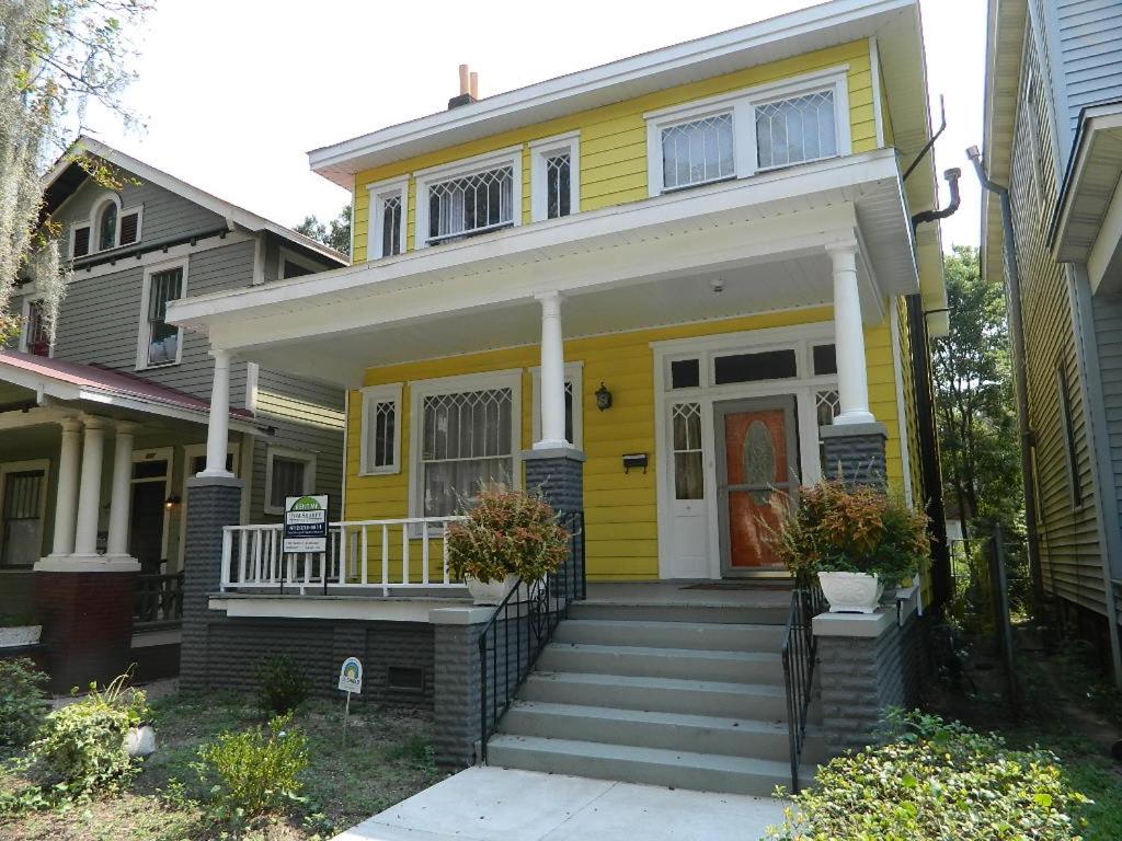 une maison jaune avec une terrasse couverte et des escaliers. dans l'établissement Marie@305, à Savannah