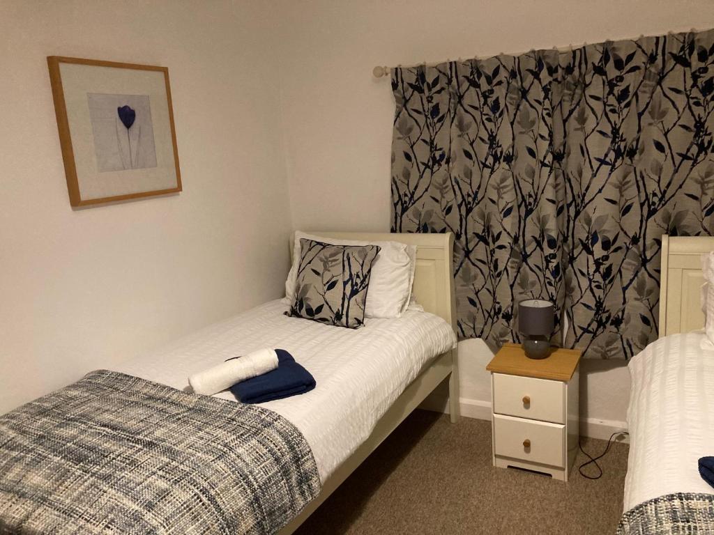 a small bedroom with a bed and a curtain at Holcot Cottage 