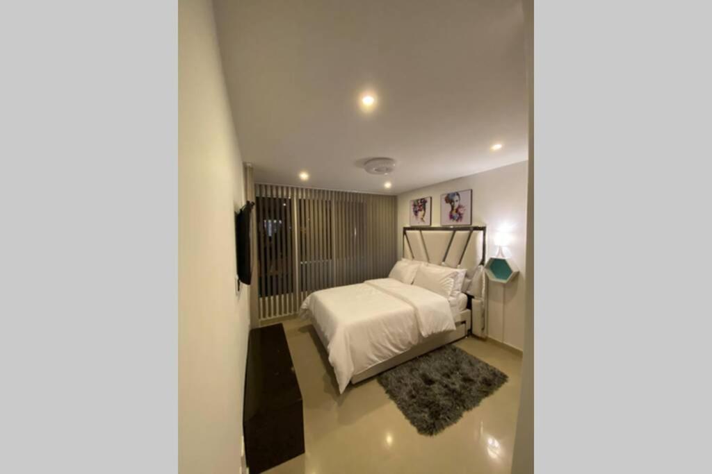 1 dormitorio con cama blanca y alfombra en Espectacular apto amoblado, bien ubicado 3 piso, en Manizales